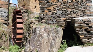 Ein Steinhaus mit einer Holztreppe, die zu einem steinernen Bogen führt.