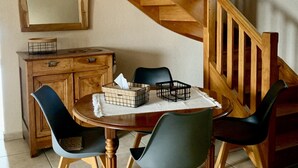 A dining area with a wooden staircase, a wooden cabinet, and a round table with chairs.
