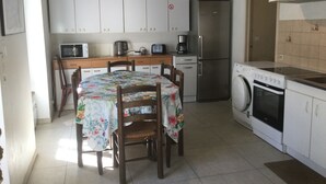 A compact kitchen with white cabinets, a refrigerator, a microwave, a coffee maker, and a dishwasher. - DINARD VACATION RENTAL HOUSE (Dinard)