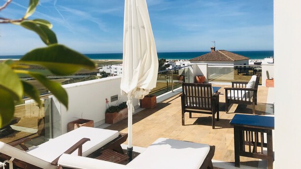 A rooftop terrace with a view of the sea, a white umbrella, and outdoor furniture. - Luxury Penthouse in Conil de la Frontera - Breathtaking Sea views. (Conil de la Frontera)