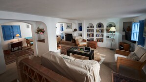 Ein geräumiges Wohnzimmer mit Kamin, bequemen Sitzgelegenheiten, einem Bücherregal und einem Fernseher.