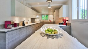 Una cocina moderna con una isla central, electrodomésticos integrados y un amplio ventanal que proporciona luz natural.