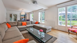 Una sala de estar moderna con un sofá modular, una mesa de centro de vidrio y ventanas amplias que ofrecen vistas al exterior.