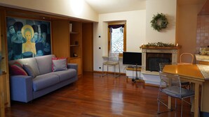 Un salón con sofá, televisión, chimenea y un cuadro en la pared.