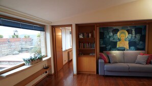 Una sala de estar con un sofá, una estantería y un cuadro grande.