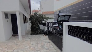 A paved courtyard with stone tiles, white walls, and a black metal fence.
