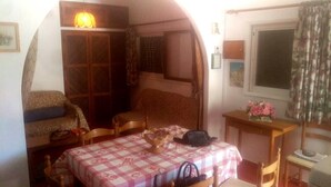A cozy room with a checkered table, a bed, a wooden cabinet, and a window with curtains.