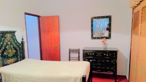 A bedroom with two beds, a dresser, a chair, and a mirror on the wall.