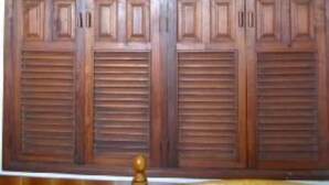 A large wooden wardrobe with multiple compartments and louvered doors.