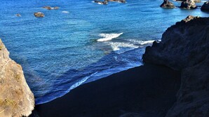 A coastal landscape with rocky outcrops and a clear blue sea.
