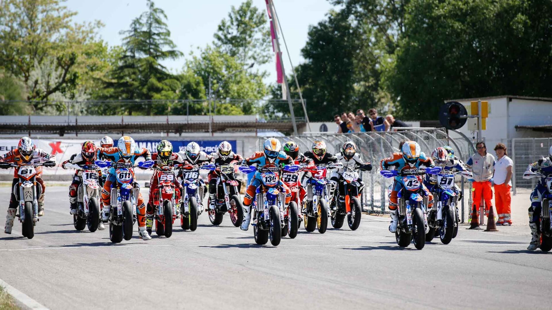 A group of motorcyclists lined up on a race track.