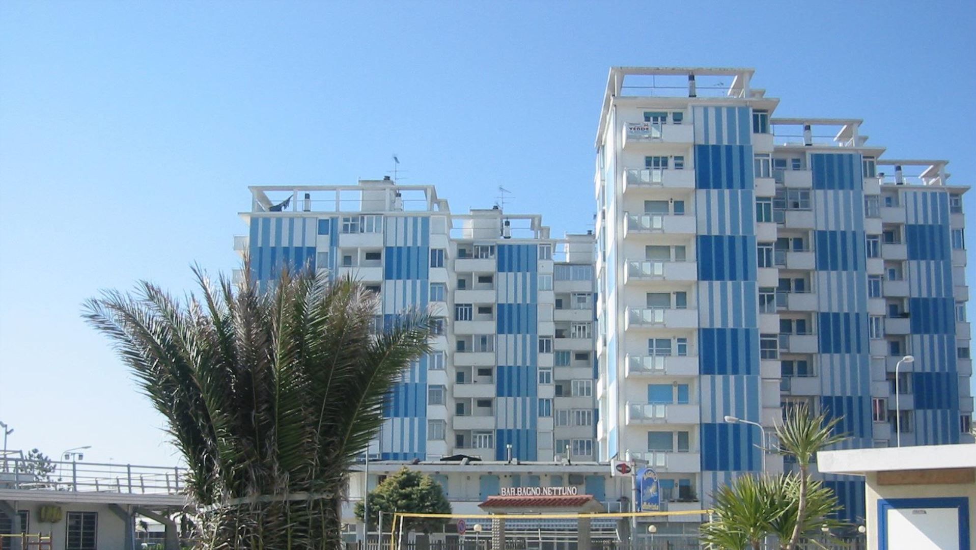 A multi-story residential building with a modern architectural design, featuring a mix of balconies and windows.