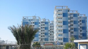 Um edifício residencial de vários andares com design arquitetônico moderno, apresentando uma combinação de varandas e janelas.