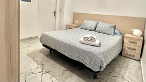 A bedroom with a bed, a nightstand, a bedside table, a hanging light, and a door. - Suitable. Bright 10 min from the BEACH walking and 3 min from the PORT (València)