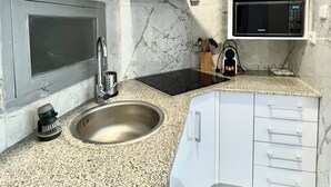 A modern kitchen with a stainless steel sink, a microwave, and white cabinets. - Suitable. Bright 10 min from the BEACH walking and 3 min from the PORT (València)