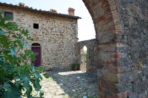 A stone building with a red door, a small window, and a brick archway.