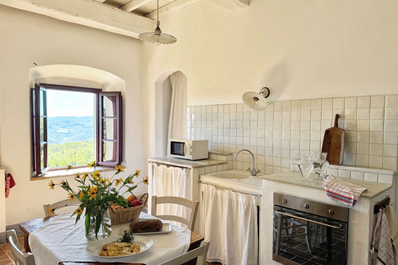 Una cocina con vistas, una mesa de comedor con un florero, un microondas y un fregadero.
