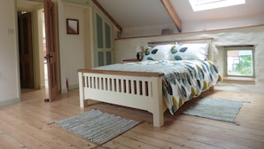 Un dormitorio con cama de madera, tragaluz, una puerta y una ventana.