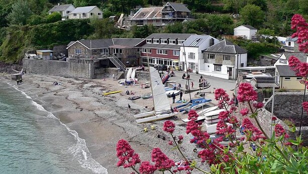 Un pueblo costero con playa, casas y un muro de piedra.