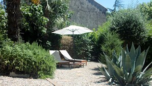 Een tuin met een zithoek, een grote parasol en een opvallende agaveplant.