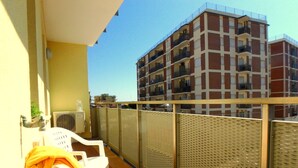 Een balkon met een witte stoel, een tafeltje en een waterdispenser.