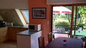 Cocina compacta con microondas, refrigerador pequeño y ventana con vistas a un jardín.