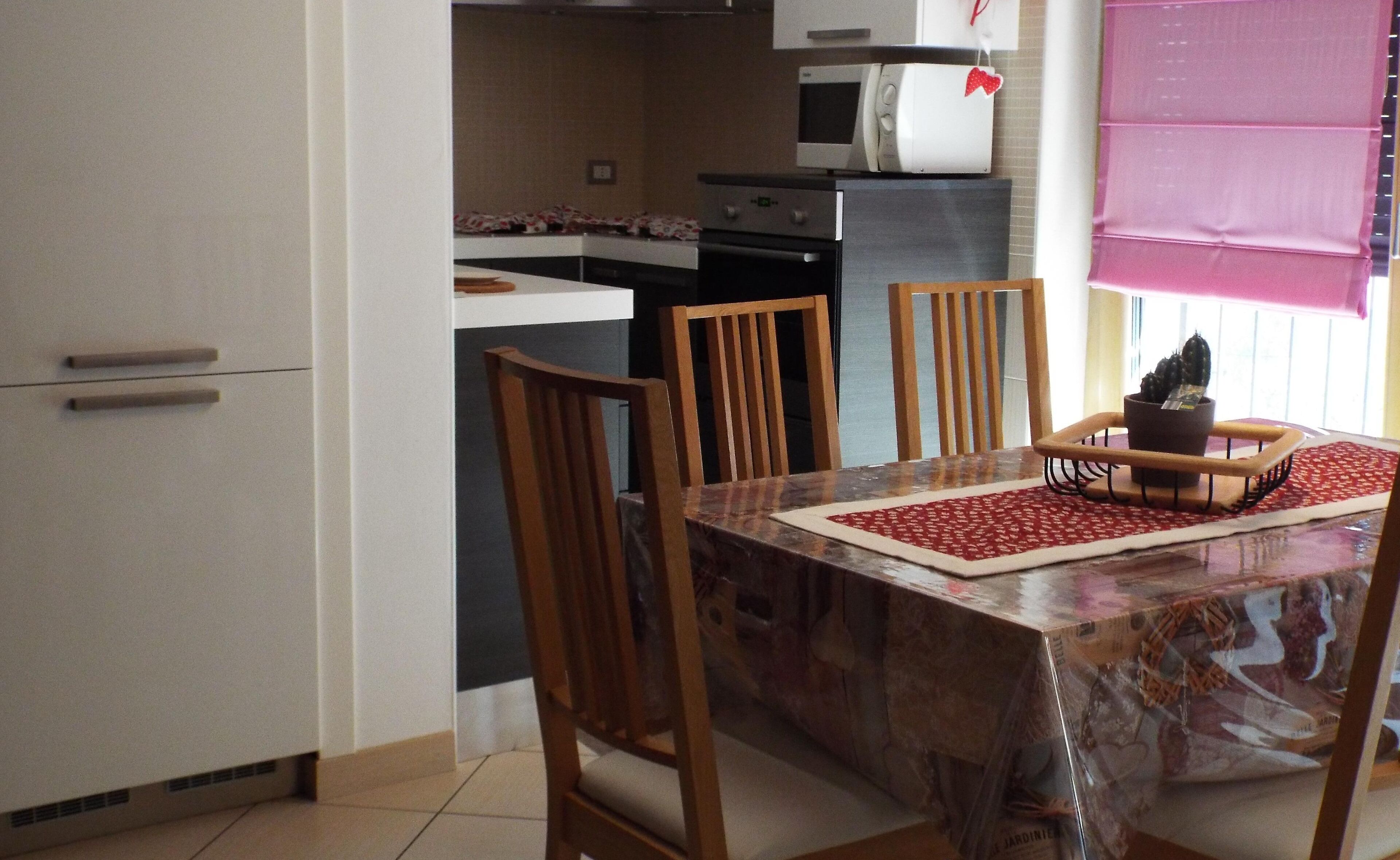 A compact kitchen with a microwave, oven, and a small dining area with a table and chairs.