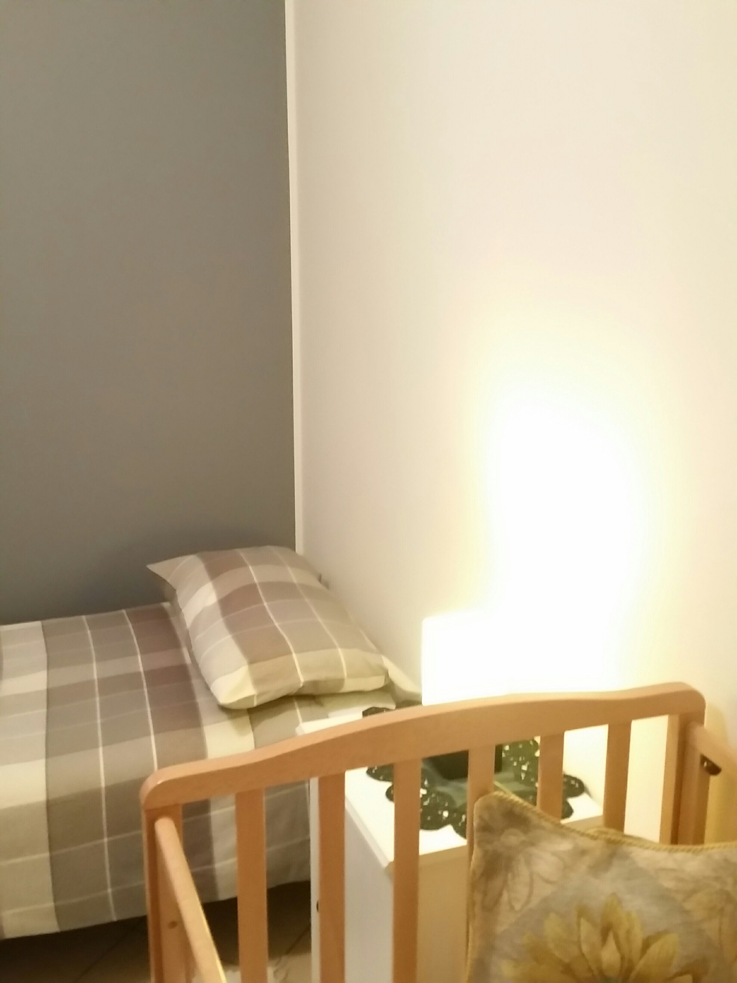 A bedroom with a bed, a nightstand, and a wooden crib.