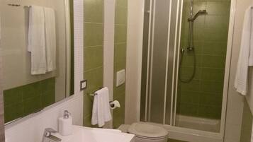Un baño con ducha, inodoro, lavamanos y espejo.