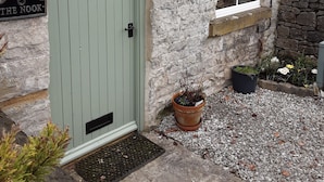 A stone building with a green door, a heart-shaped window, and a small window with a green shutter. - THE NOOK, a cosy 3 bed cottage, newly renovated & pet friendly in Tideswell (Tideswell, Derbyshire)
