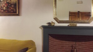 Ein Zimmer mit einem gelben Sofa, einem Kamin mit Spiegel darüber und einem Bild an der Wand.