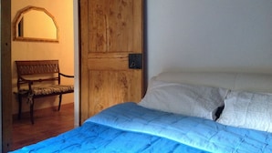 Ein Schlafzimmer mit Holztür, einer Sitzbank und einem Bett mit blauer Bettdecke.