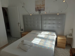 A hotel room with a large bed, two bedside tables, a headboard, and a poster on the wall.