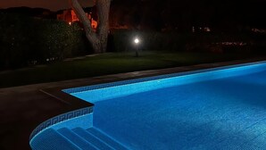 A swimming pool with a tree and a house in the background.