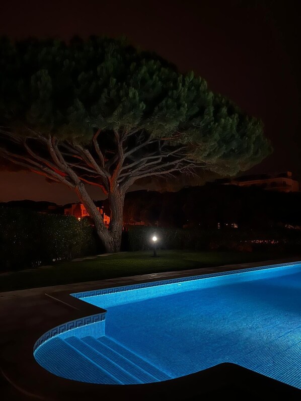 A swimming pool with a tree and a house in the background.