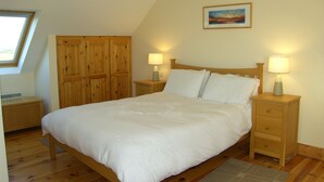 Ein Schlafzimmer mit einem hölzernen Bett, zwei Nachttischen mit Lampen, einem Holzschrank, einem Oberlicht und einem Gemälde an der Wand.