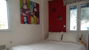 A bedroom with a white bed, a red accent wall, and a colorful poster. - Elegant and cozy apartment (Santorini)