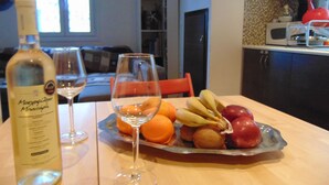 A dining table with a bottle of wine, a glass, and a fruit platter. - Elegant and cozy apartment (Santorini)