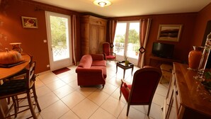 A living room with a sofa, chairs, a TV, and a dining table. - GITE CLOSE TO PUY DU FOU 10 mins FROM VILLA MAGDALENA (Sèvremont)