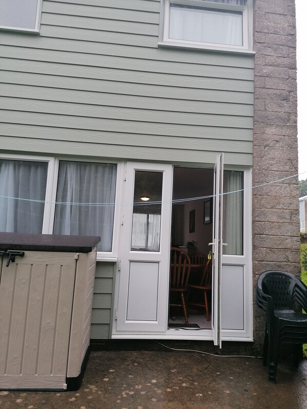 A residential building with a sliding glass door leading to a patio area. - 'Le Chalet' 2 bedroom sleeps 3, short walk to beach, free wifi and parking. (Freshwater East)