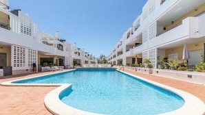 Un hôtel moderne doté d’une piscine centrale, de nombreux balcons et offrant une vue sur un ciel dégagé.