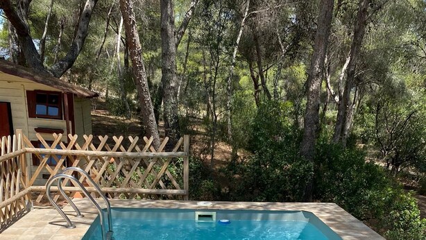 Une piscine rectangulaire à l’eau d’un bleu limpide, entourée d’une terrasse en bois et d’une clôture en bois.