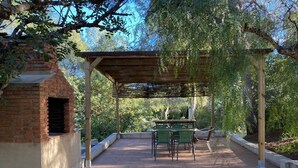 Un patio couvert avec un four en briques, des sièges d’extérieur et une pergola.