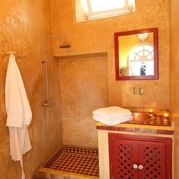 A bathroom with a shower, a sink with a mirror, and a towel rack.