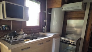 Cocina compacta equipada con microondas, fregadero, estufa y un refrigerador pequeño.