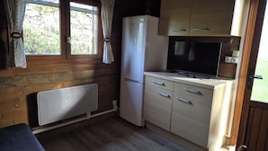 Cocina compacta con paredes de madera, un refrigerador blanco, un microondas y un lavamanos.