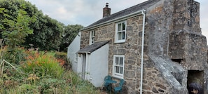 A stone house with a white exterior, a small porch, and a window.