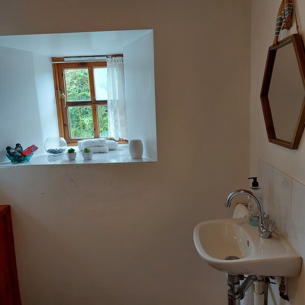 Une salle de bain avec une fenêtre, un lavabo et des articles de toilette.
