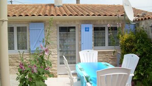 A building with a tiled roof, a satellite dish, and a table with chairs in the foreground. - Au Calme Stone house, large pool. near sea1,.5 km classified 4 stars (Saint-Pierre-D'oléron)