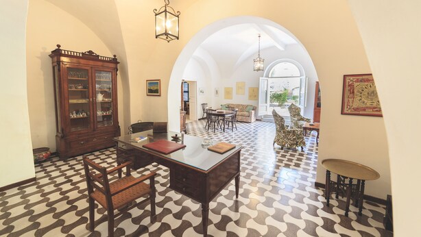 A spacious room with a patterned floor, a wooden cabinet, a dining table with chairs, and an arched doorway leading to another room. - Stately residence in the center, with garden (Vasto)